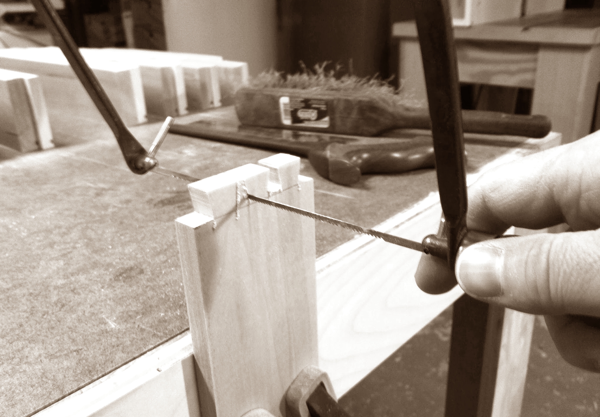 Using coping saw to cut waste between tails, staying just off the lines